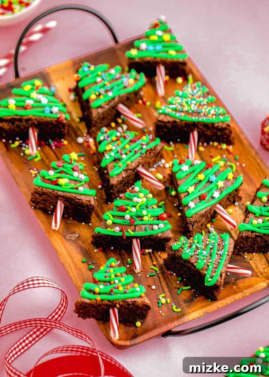 A stunning presentation of Christmas tree brownies arranged neatly on a rustic wooden tray with sleek black metal handles, ready to be served or shared as a festive holiday treat.