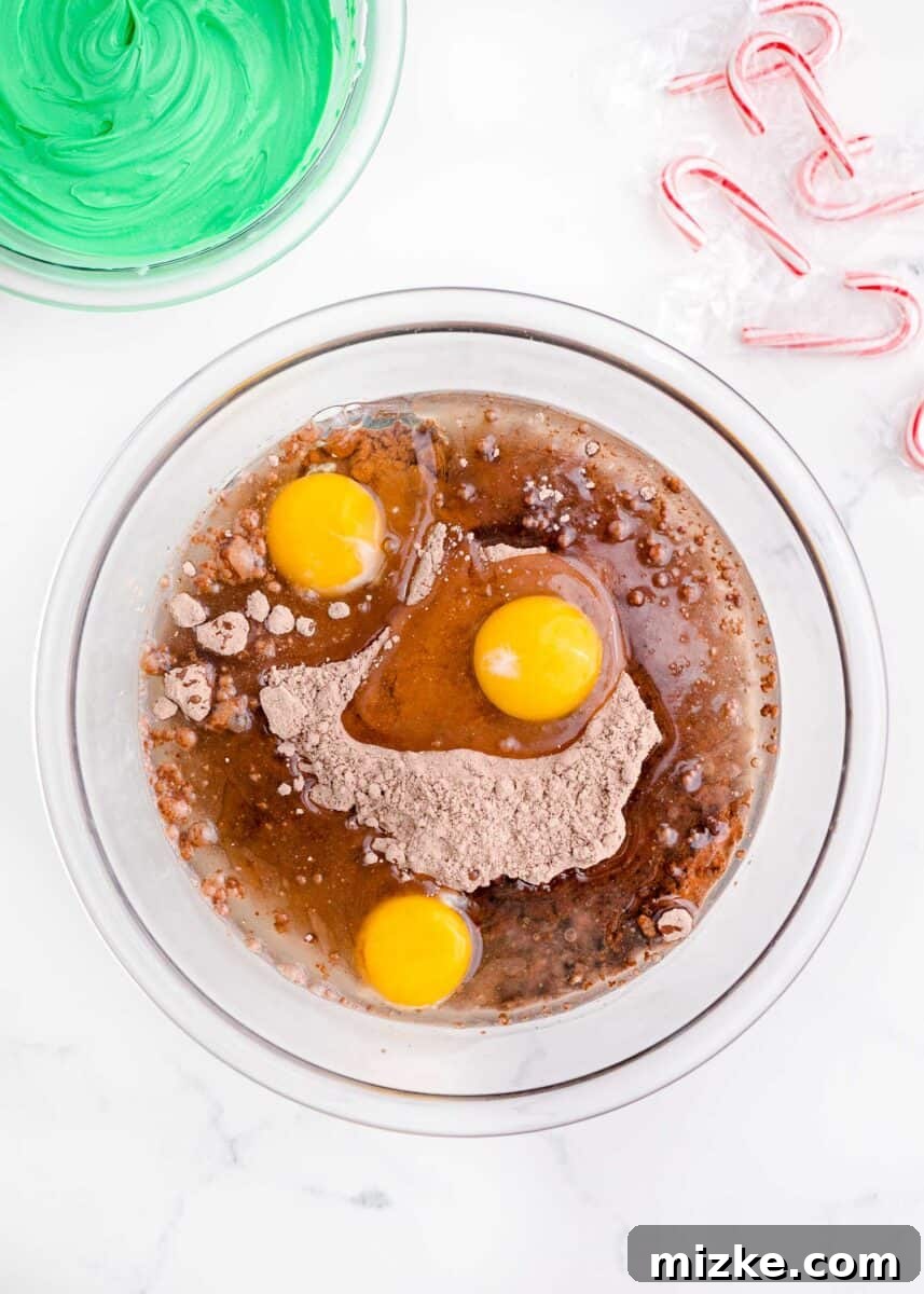 A clear bowl holds the dry brownie mix, with fresh eggs and a small dish of oil positioned beside it, ready to be combined into batter.