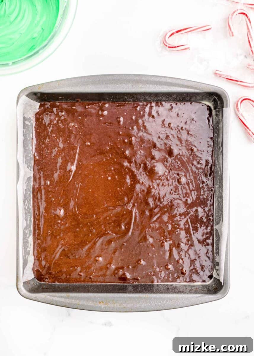 Rich brownie batter is smoothly poured and spread evenly into a 9x9 inch baking pan, ready for baking.