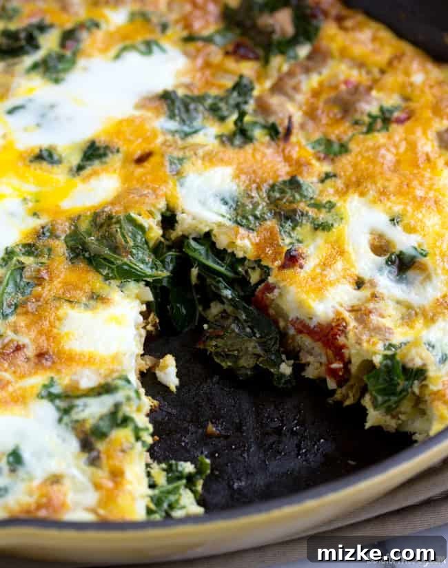This healthy vegetable frittata recipe is an easy, high-protein breakfast filled with ground turkey, kale, onions, and sun-dried tomatoes. Close up of a turkey and vegetable frittata in a cast iron skillet with a slice missing.