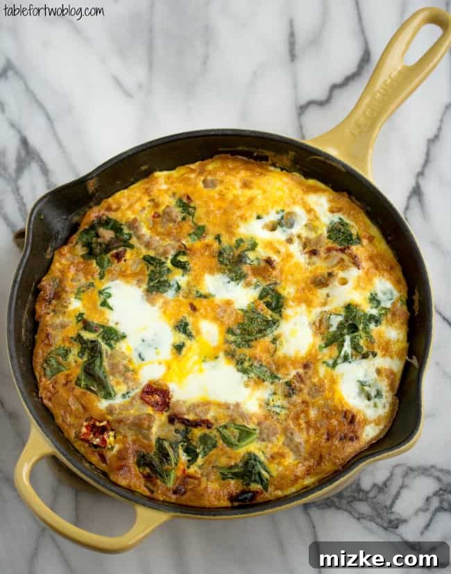 This healthy vegetable frittata recipe is an easy, high-protein breakfast filled with ground turkey, kale, onions, and sun-dried tomatoes. Overhead view of a turkey and vegetable frittata in a cast iron skillet.