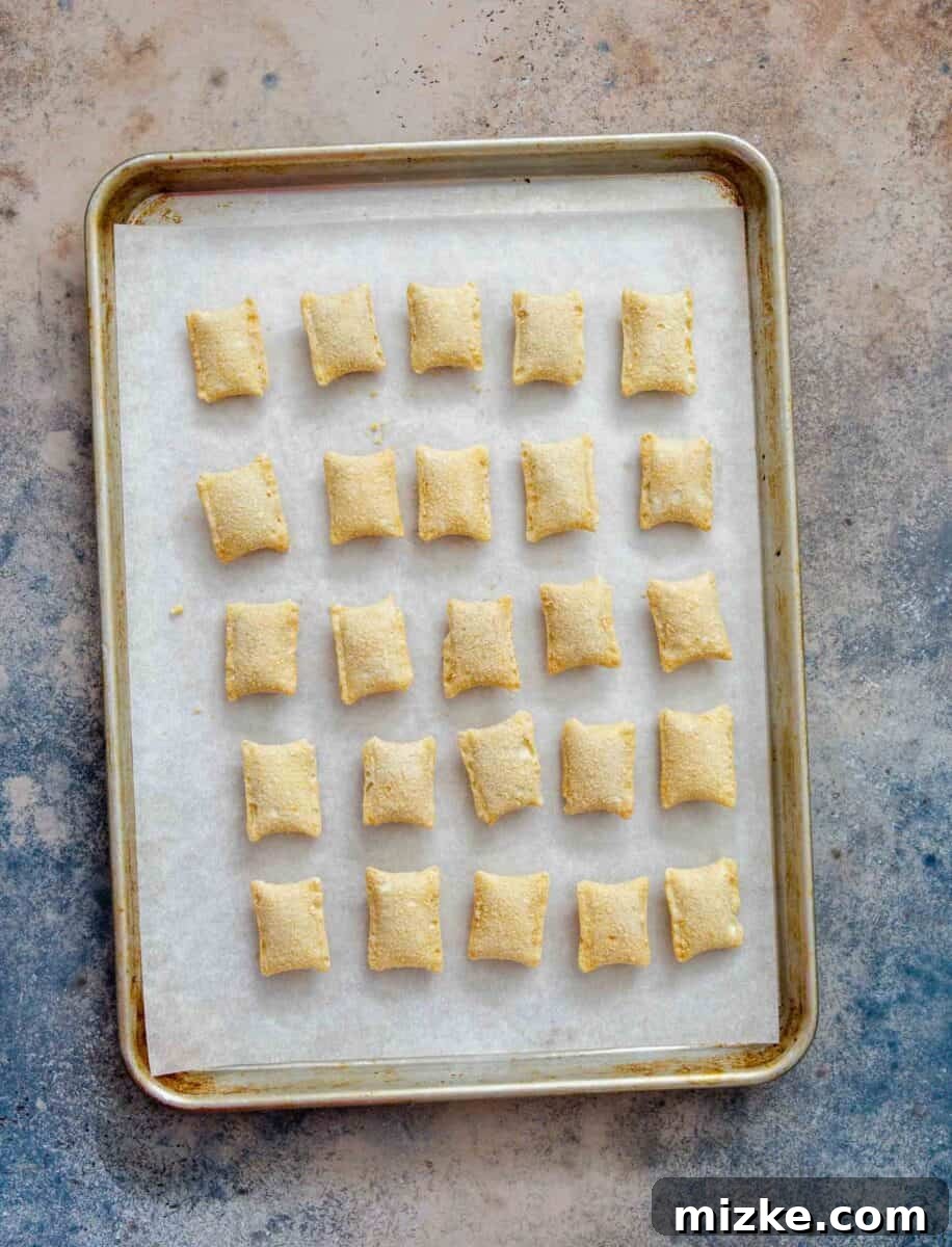 Snackable Pizza Bites 5 Frozen pizza rolls neatly arranged on a parchment paper lined rimmed baking sheet, ready for baking.