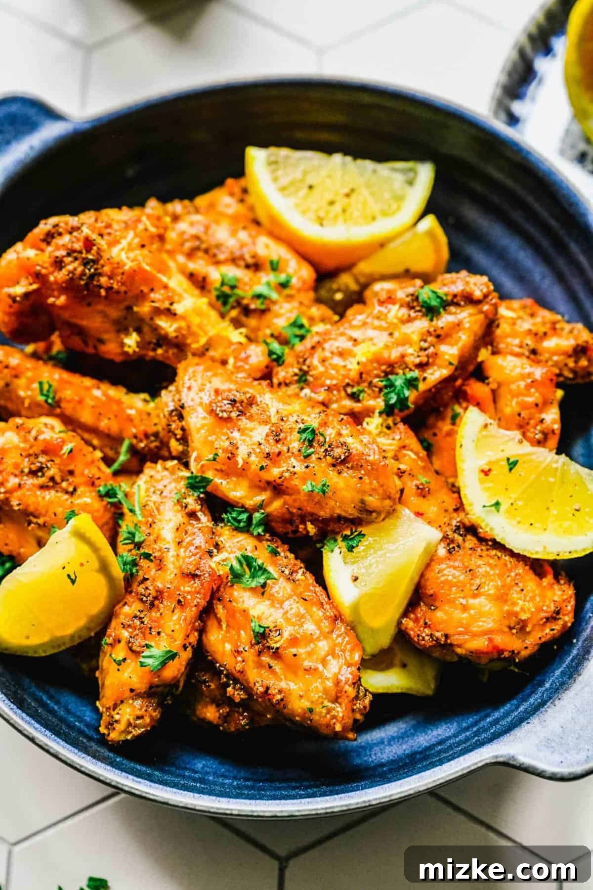 Lemon pepper chicken wings on a platter with lemon wedges, ready to serve.