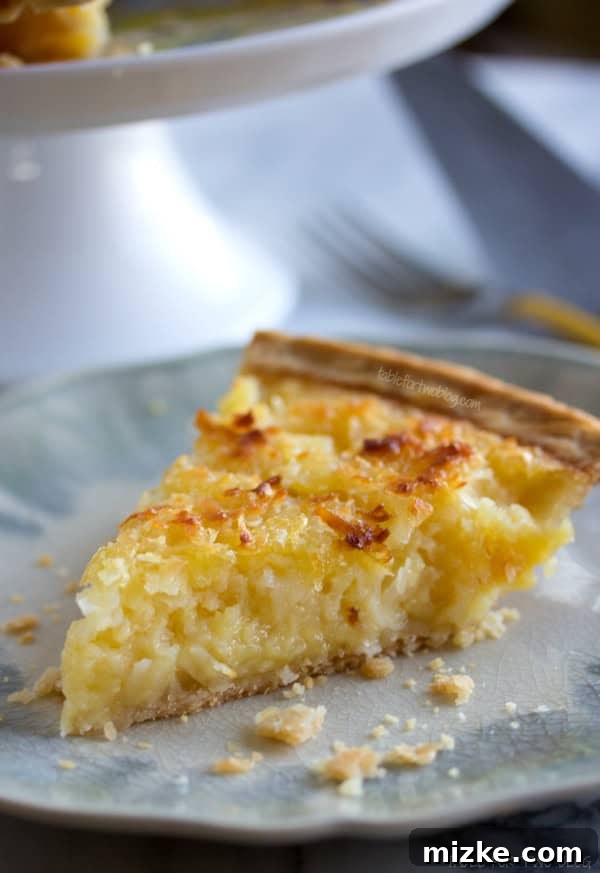 Pina Colada Inspired Pie A close-up view of a slice of Tropical Pie, revealing its rich, custardy filling studded with pineapple chunks and shredded coconut.