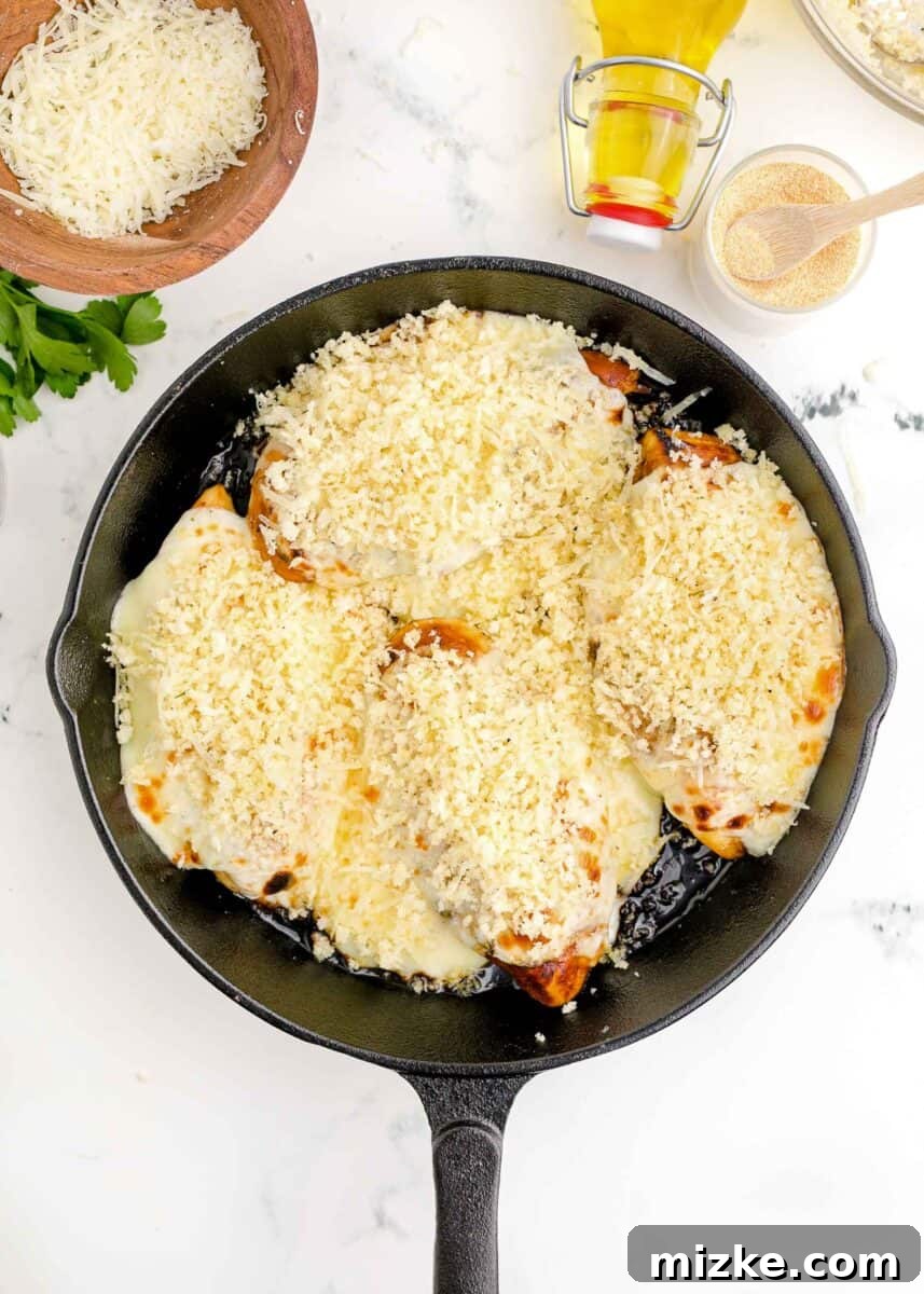 Panko breadcrumb mixture generously crumbled over melted cheese and chicken breasts in a cast iron skillet.