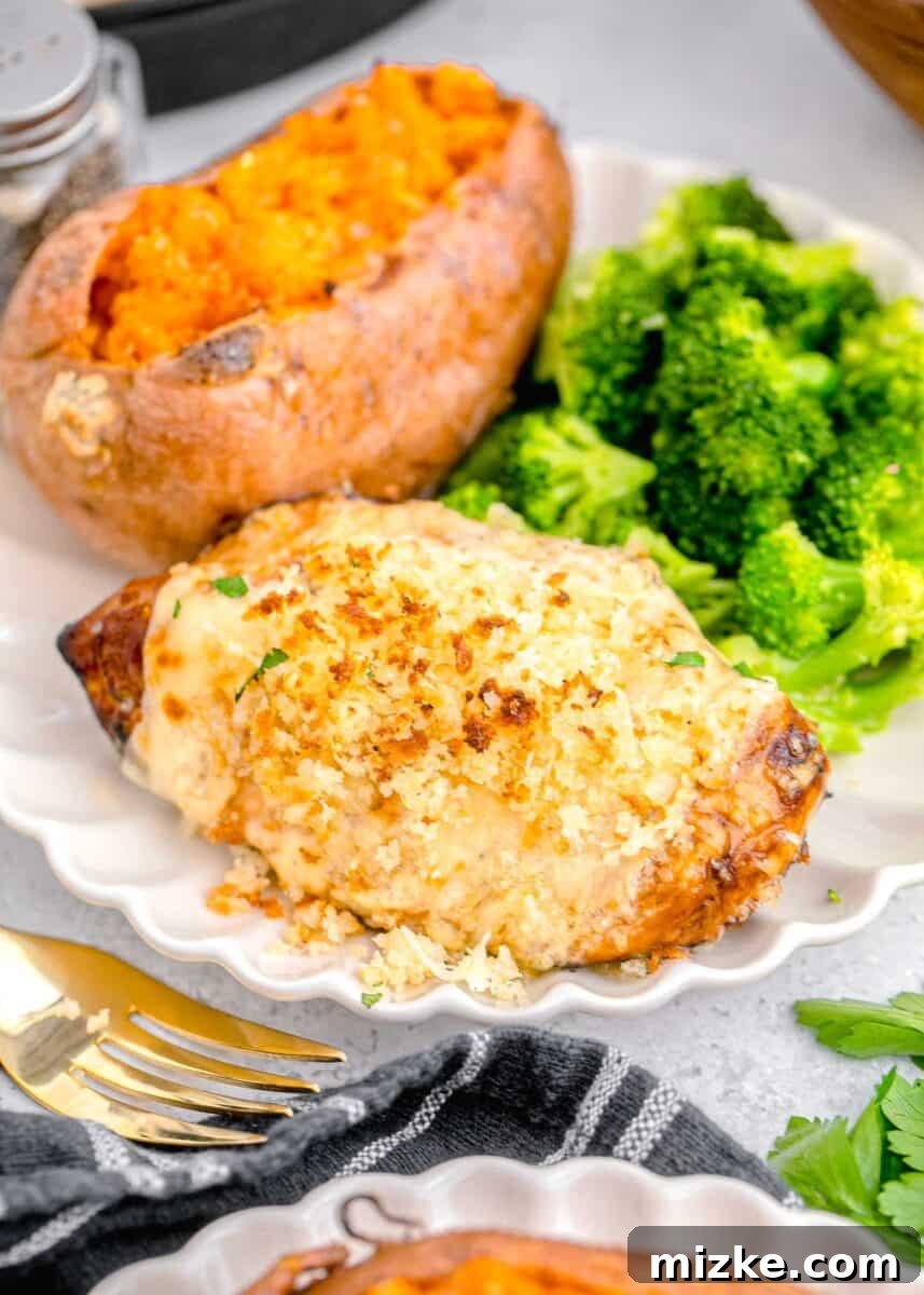 A plated Parmesan Crusted Chicken with baked sweet potato and steamed broccoli, showcasing a complete meal.