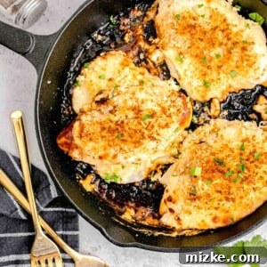 Parmesan Crusted Chicken in a cast iron skillet next to gold forks