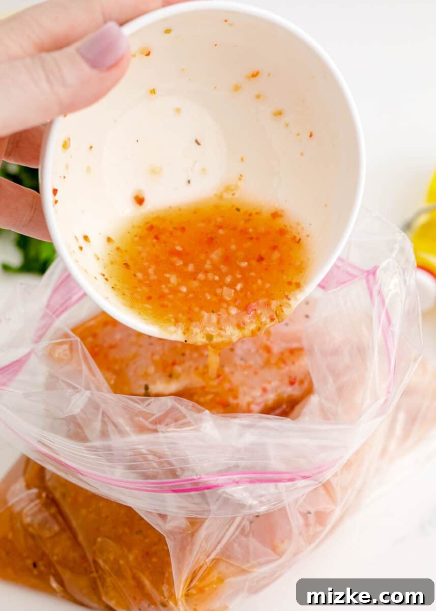 Pouring Italian dressing over chicken breasts in a plastic bag to marinate.