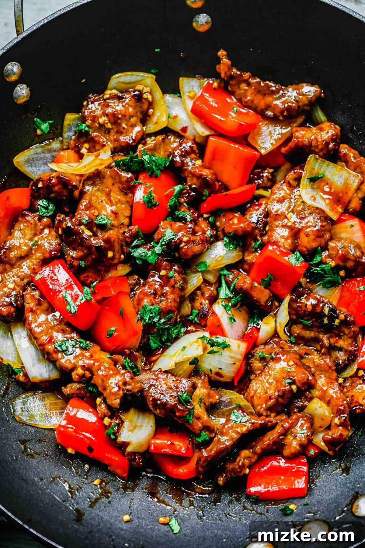 This Beijing Beef beats takeout any day. Sticky, sweet, tangy, slightly spicy sauce marries crispy bites of beef with sautéed veggies. Crispy Beijing beef with colorful bell peppers and onions simmering in a wok.