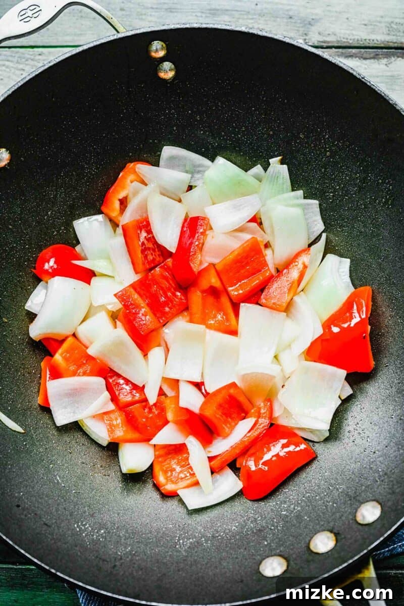 This Beijing Beef beats takeout any day. Sticky, sweet, tangy, slightly spicy sauce marries crispy bites of beef with sautéed veggies. Fresh bell peppers and onions sautéing in a hot wok.