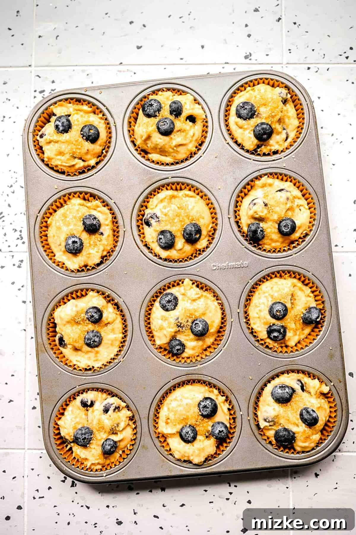 Fill muffin tins generously for large, bakery-style banana blueberry muffins. Banana blueberry muffin batter perfectly portioned into lined muffin tins, ready to be baked into delicious treats.