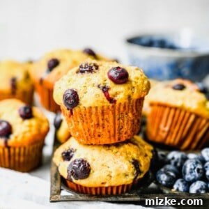 Banana blueberry muffins displayed next to fresh blueberries and a knife, ready for serving.