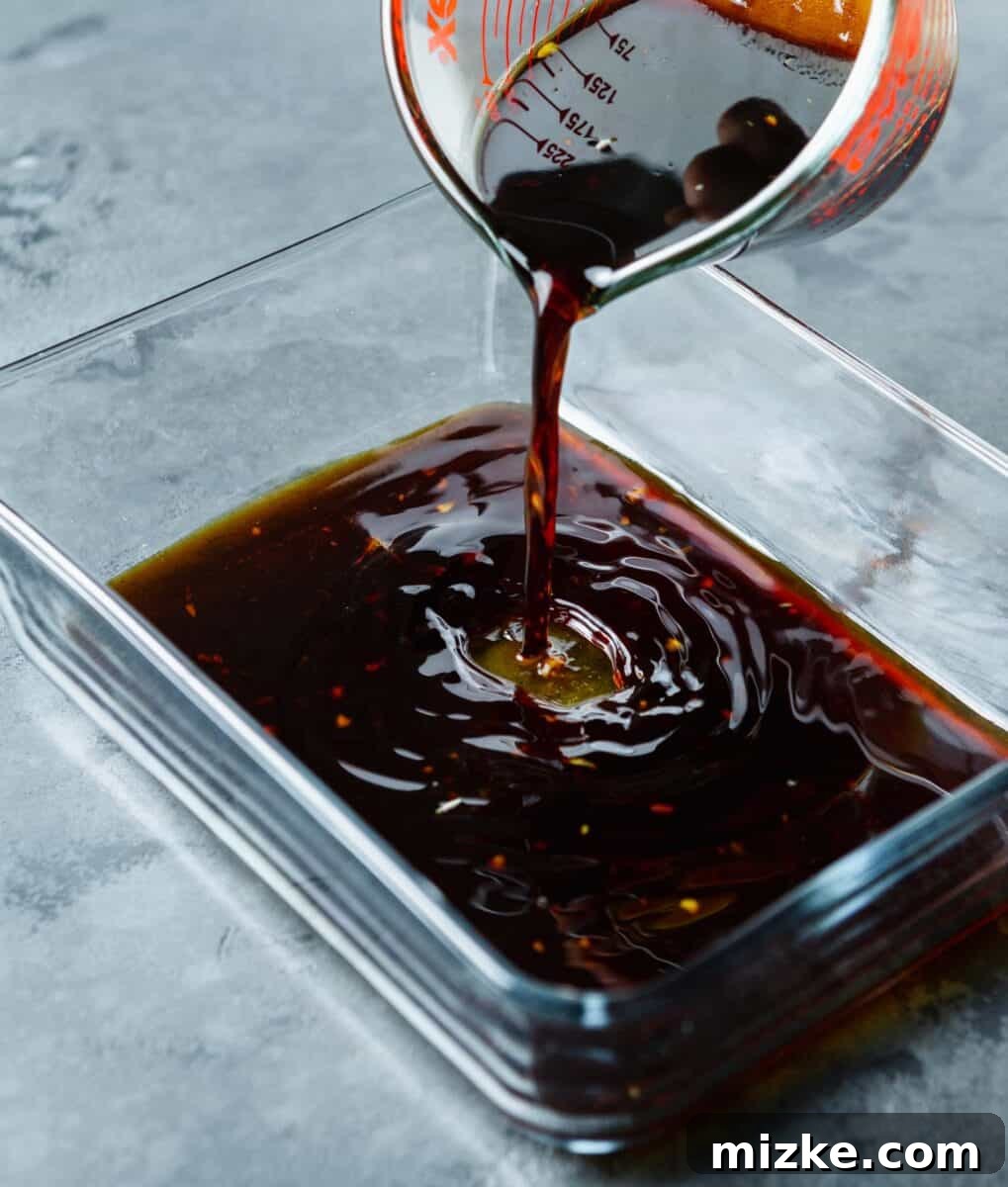 Perfect Air Fryer Teriyaki Salmon 5 Pouring homemade teriyaki marinade into a shallow glass rectangular container.