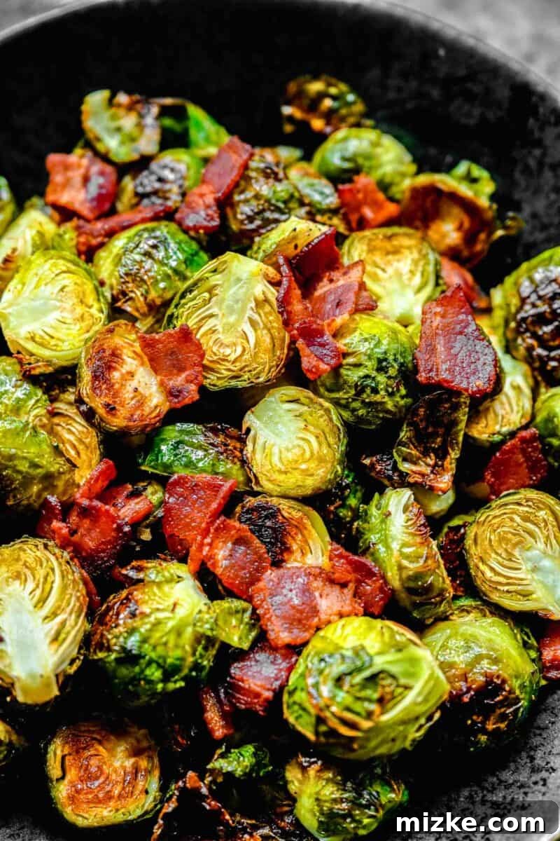 Golden Bacon Roasted Brussels Sprouts 3 Roasted brussels sprouts and crispy bacon artfully arranged in a black ceramic bowl, ready to be enjoyed.