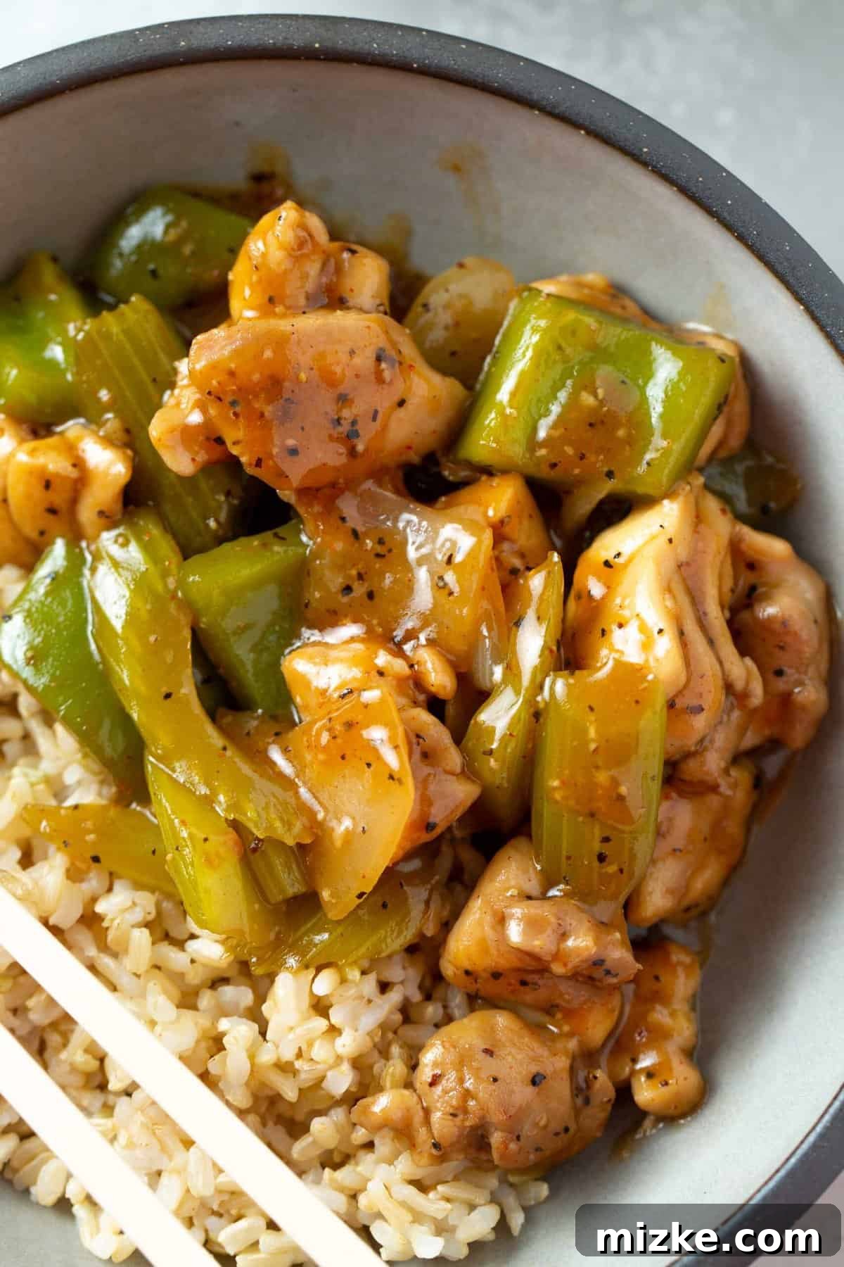 Restaurant-Quality Black Pepper Chicken 12 An overhead view of a delicious black pepper chicken dish in a bowl, served alongside perfectly cooked brown rice, highlighting the vibrant colors and appealing texture.