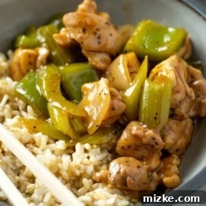 A bowl of Panda Express style black pepper chicken with brown rice, ready to be served.