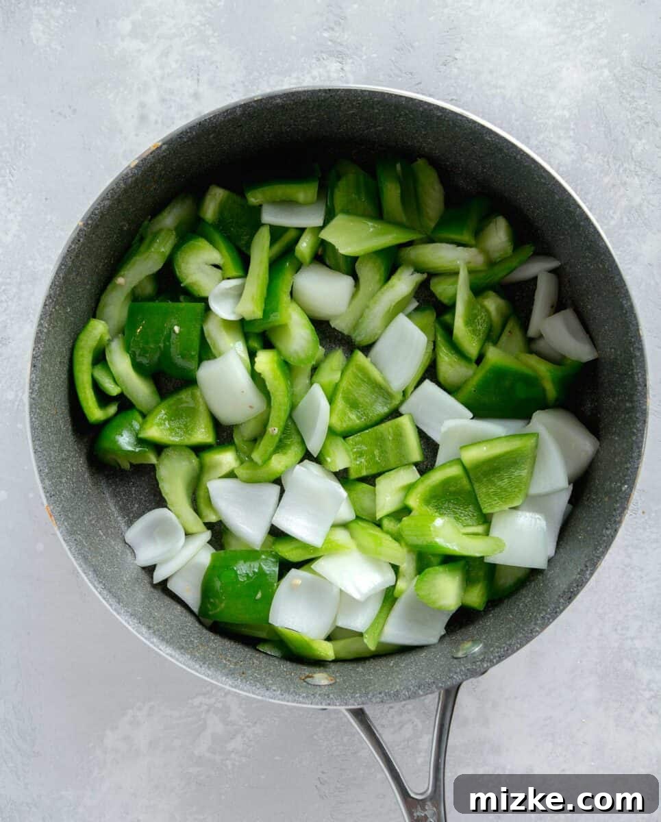 Restaurant-Quality Black Pepper Chicken 8 Vibrant green bell peppers, white onion, and crisp celery stir-frying in a nonstick skillet, softening to perfection.