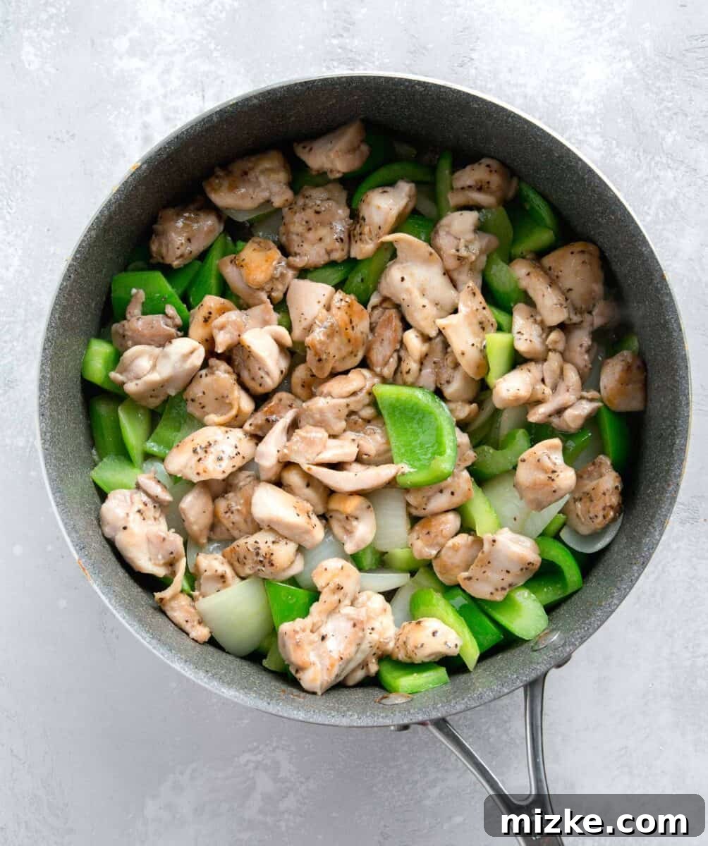 Restaurant-Quality Black Pepper Chicken 9 The partially cooked chicken pieces reunited with the sautéed green bell peppers, onions, and celery in the skillet, ready for the sauce.