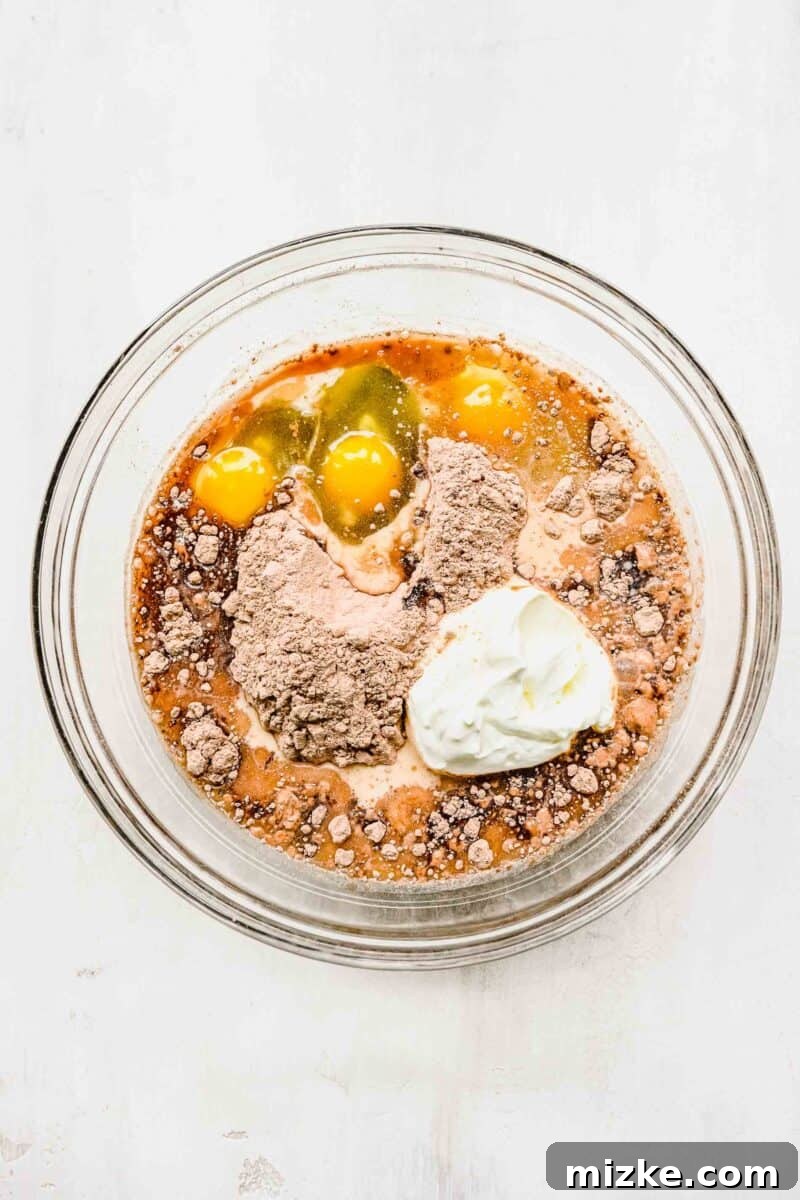 Decadent Chocolate Pudding Poke Cake 4 Smooth, rich chocolate cake batter in a clear mixing bowl, ready for baking.