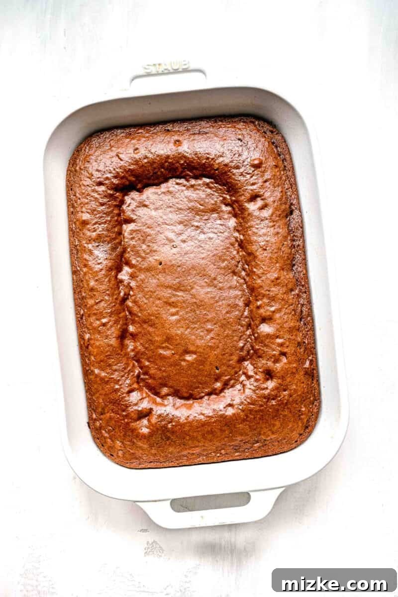 Decadent Chocolate Pudding Poke Cake 6 The golden-brown, perfectly baked base of the chocolate pudding cake resting in a white baking dish.
