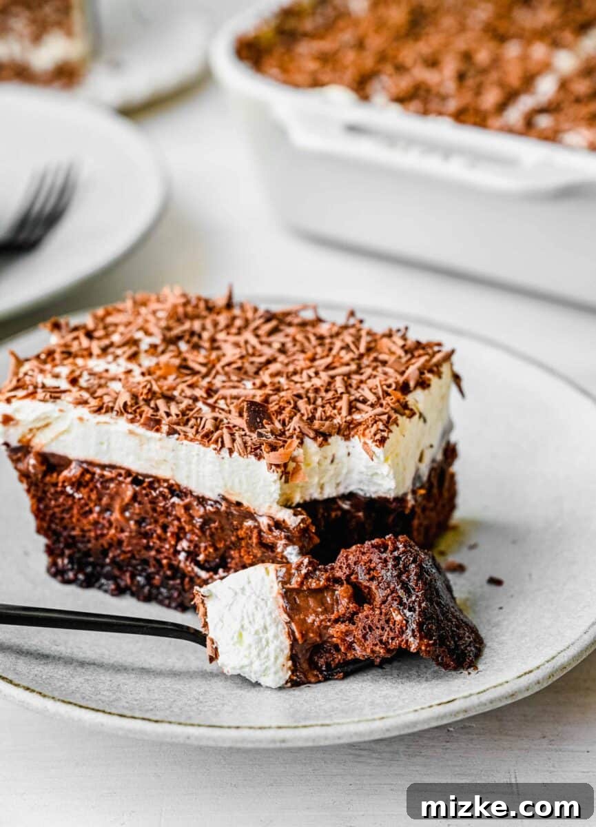 Decadent Chocolate Pudding Poke Cake 8 A perfectly cut corner piece of rich chocolate pudding cake, with a dark fork gently breaking off a bite on a pristine white plate, highlighting the gooey center.