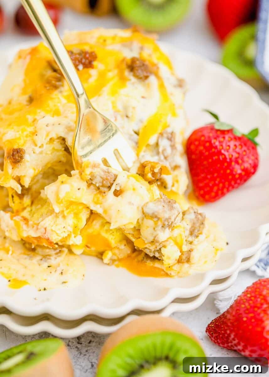 Southern Comfort Biscuit Bake 14 a fork in the center of biscuits and gravy casserole with strawberries and kiwis on the plate