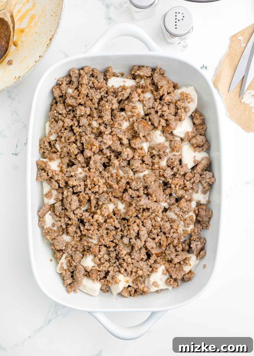 Southern Comfort Biscuit Bake 6 browned sausage pieces on top of quartered biscuits in a white baking dish