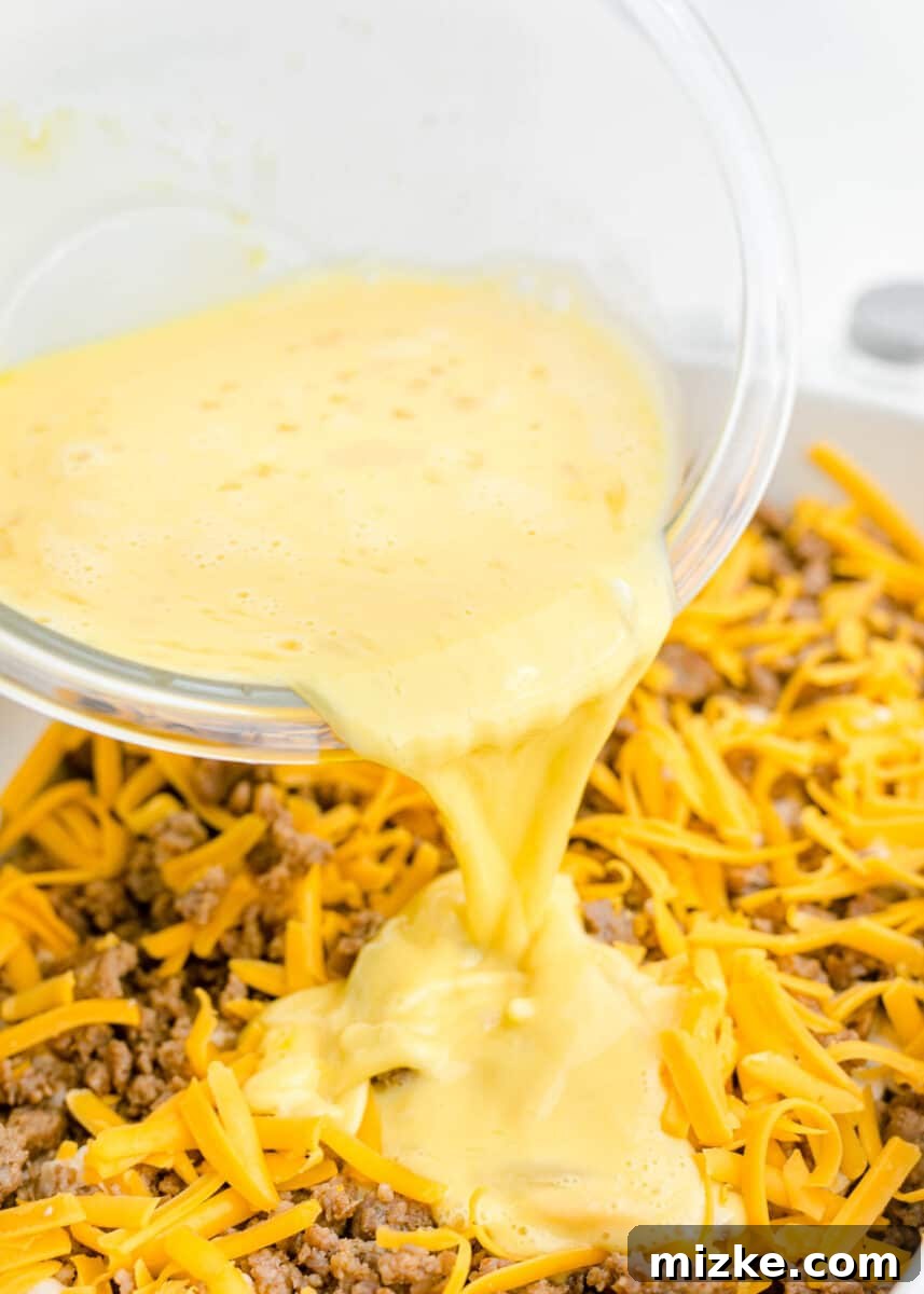 Southern Comfort Biscuit Bake 8 egg and milk mixture being poured on top of cheese and sausage mixtuer