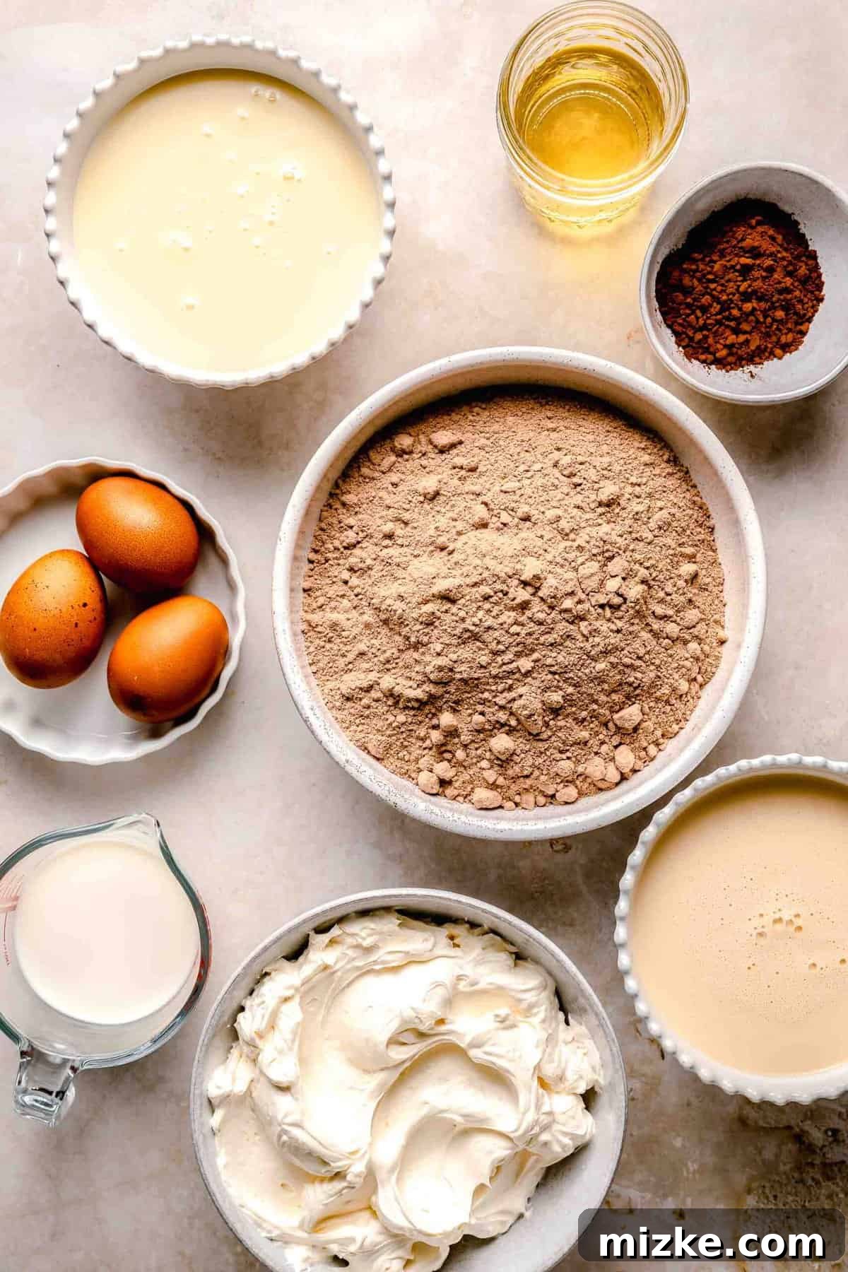 Chocolate cake is soaked in 3 kinds of milk and topped with chocolate Cool Whip and shaved chocolate in this spin on tres leches cake. Assorted ingredients for chocolate tres leches cake, neatly arranged in bowls.