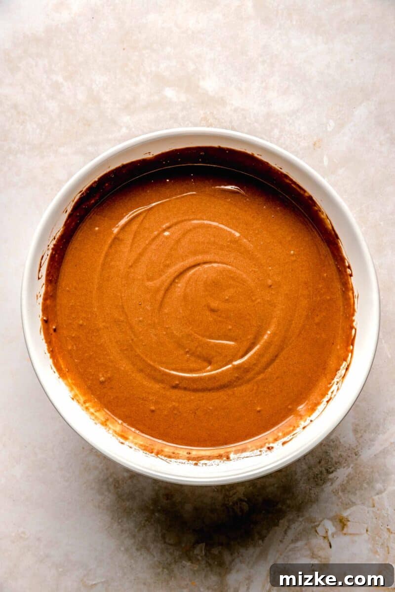 Chocolate cake is soaked in 3 kinds of milk and topped with chocolate Cool Whip and shaved chocolate in this spin on tres leches cake. Smooth, rich chocolate cake batter in a bowl, ready for baking.