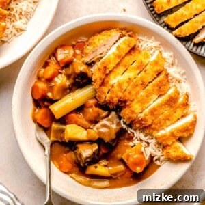 Katsu chicken curry served in a bowl over rice with a fork near a plate of chicken katsu.