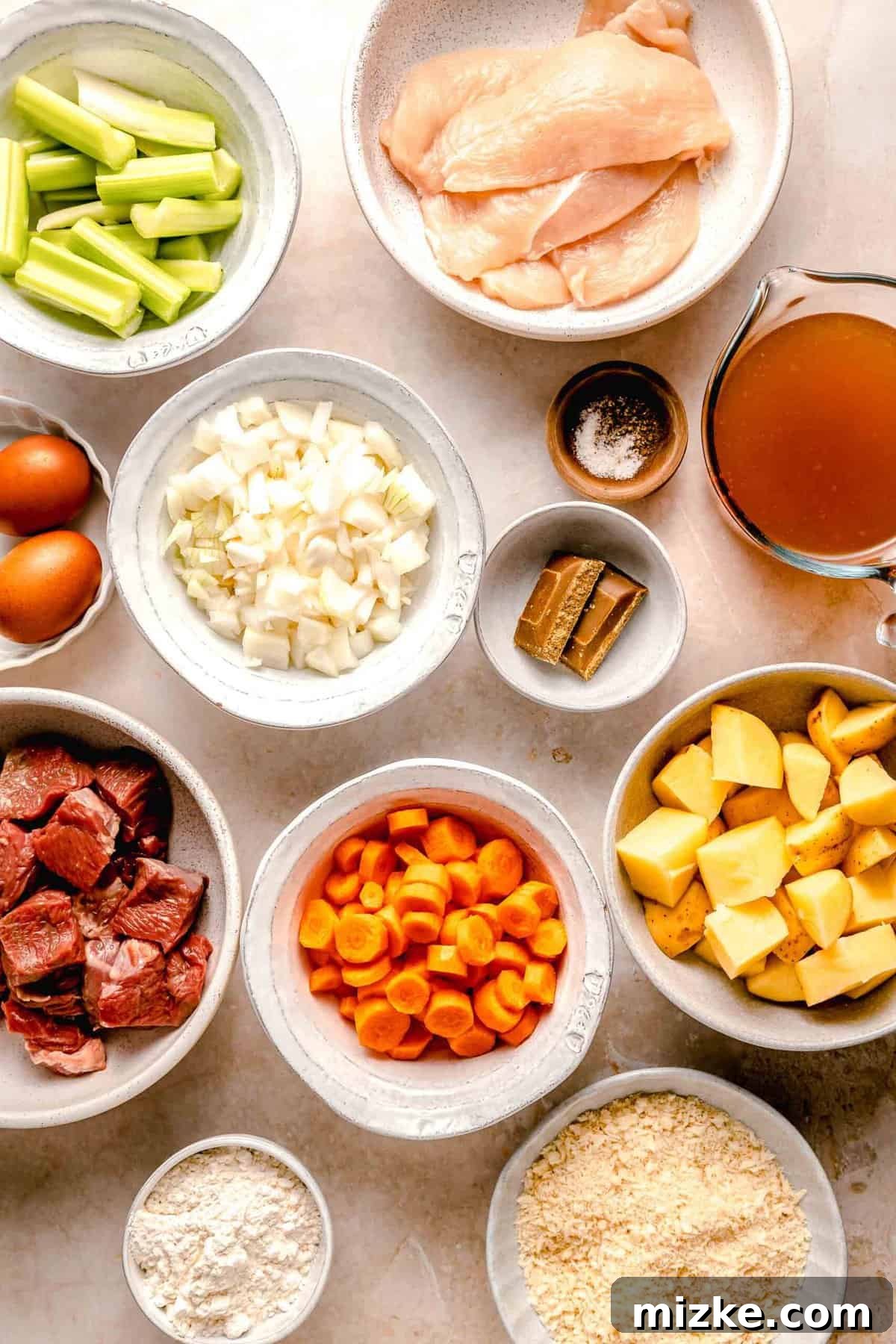 Essential ingredients for creating a delicious Chicken Katsu Curry from scratch. Fresh ingredients for homemade Chicken Katsu Curry meticulously arranged in separate bowls, including cubed chuck roast, diced onions, sliced carrots, quartered potatoes, and panko breadcrumbs, ready for preparation.