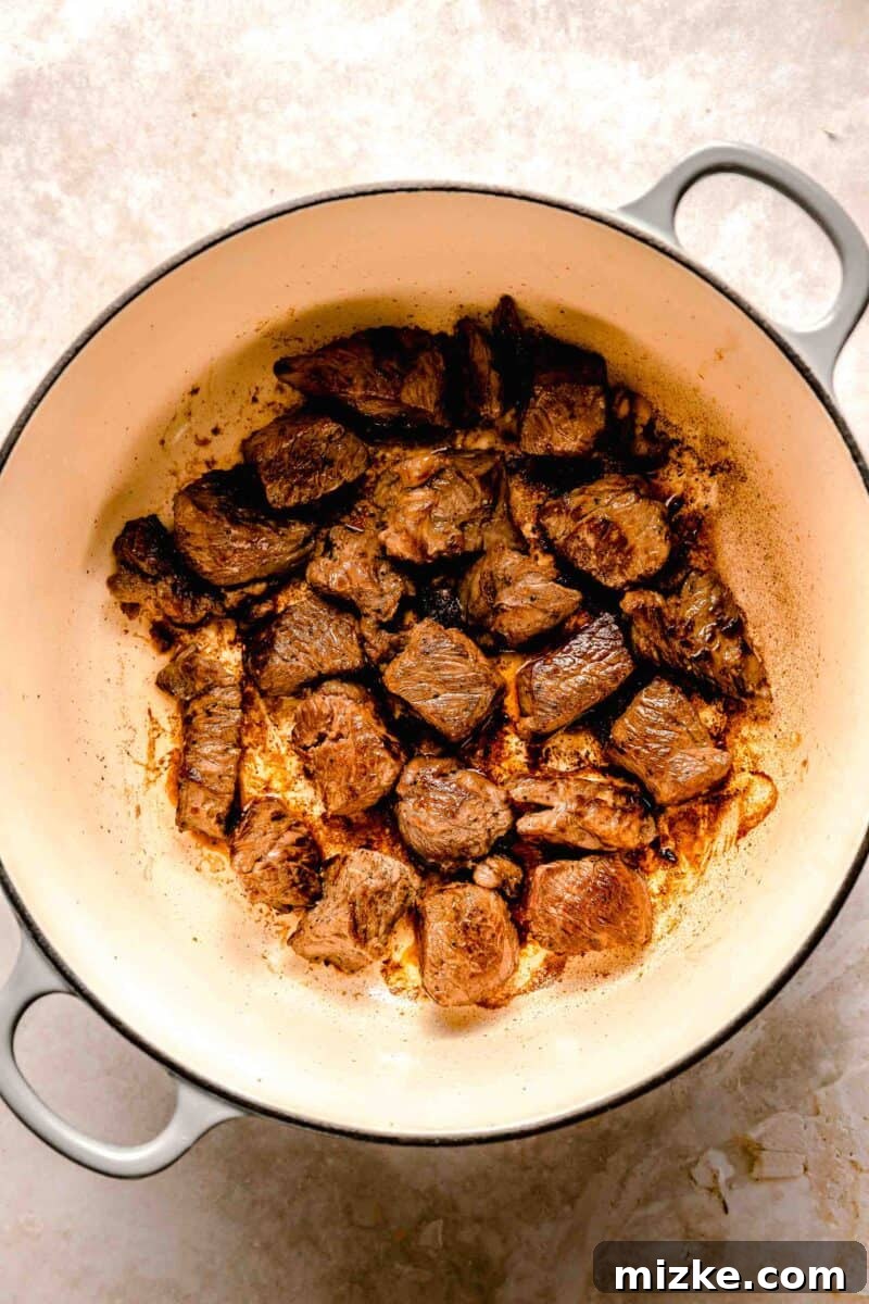 Browning chuck roast for a flavorful curry base. Cubed chuck roast browning in a heavy-bottomed skillet, developing a rich, savory crust for the Japanese beef curry.