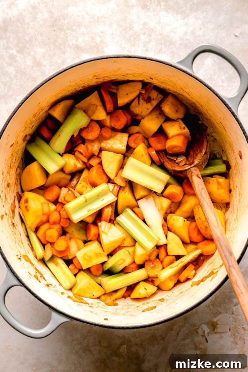 Sautéing fresh vegetables for a hearty Japanese curry. Diced onions, sliced carrots, and quartered potatoes sautéing in a skillet, softening and releasing their aromatic flavors for the Japanese curry.