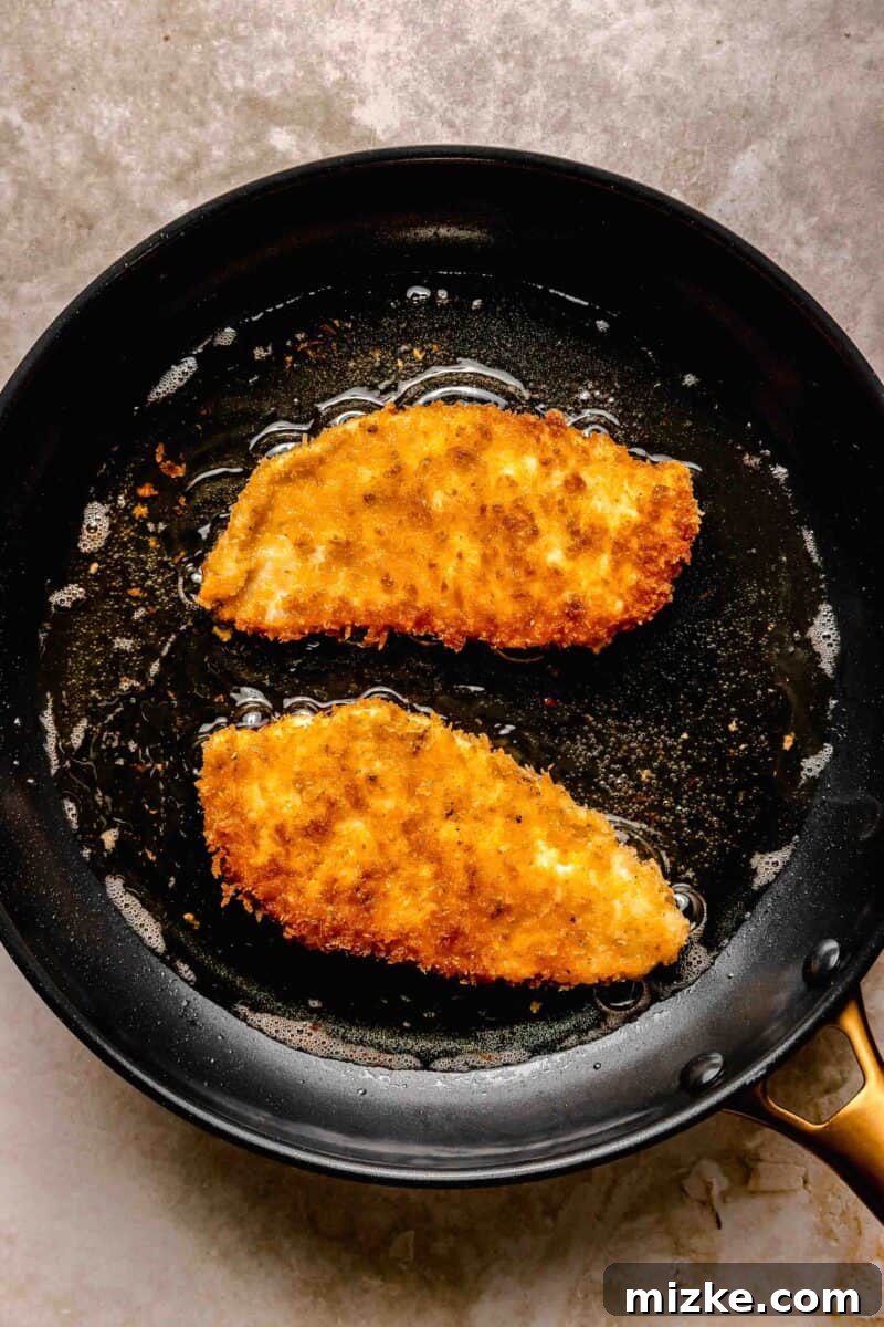 Frying chicken katsu to golden perfection. Golden brown chicken katsu frying in hot vegetable oil in a skillet, creating a wonderfully crispy crust.