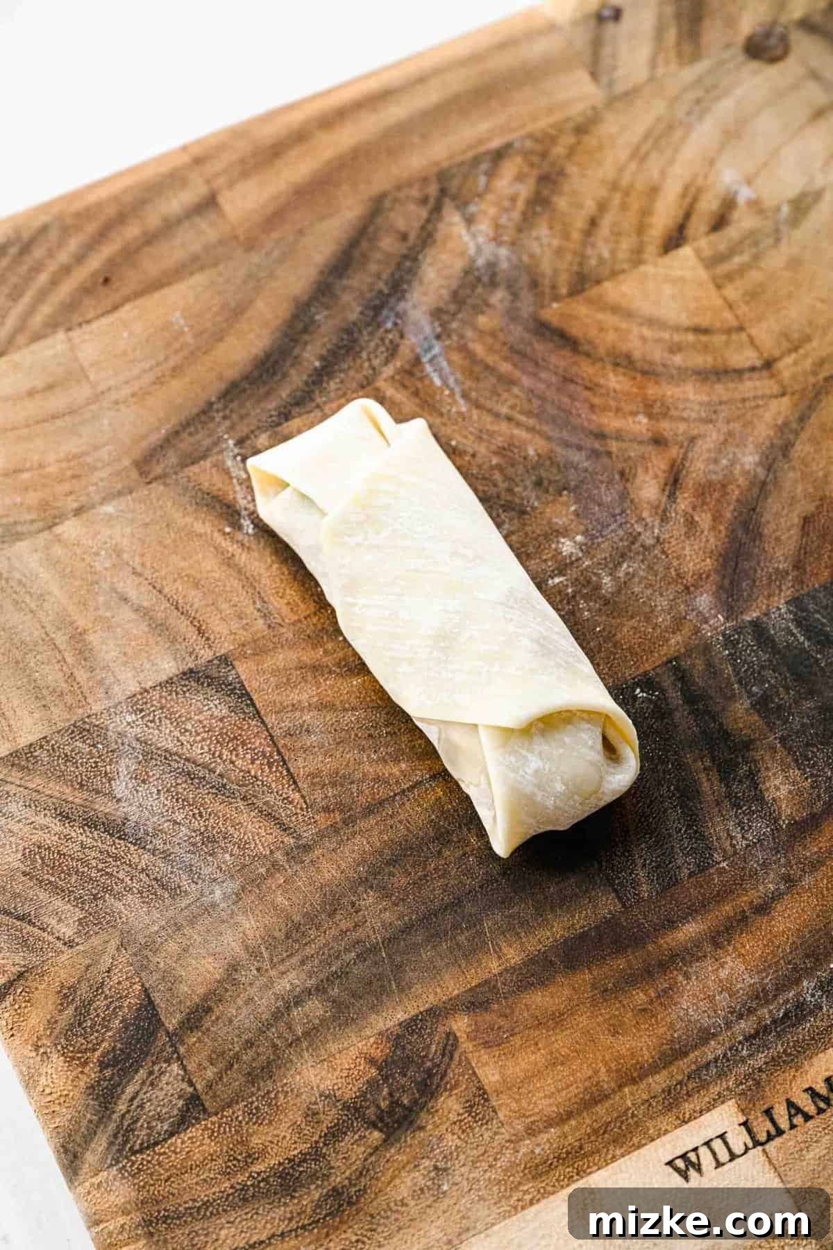 A crispy golden spring roll ready to be fried.
