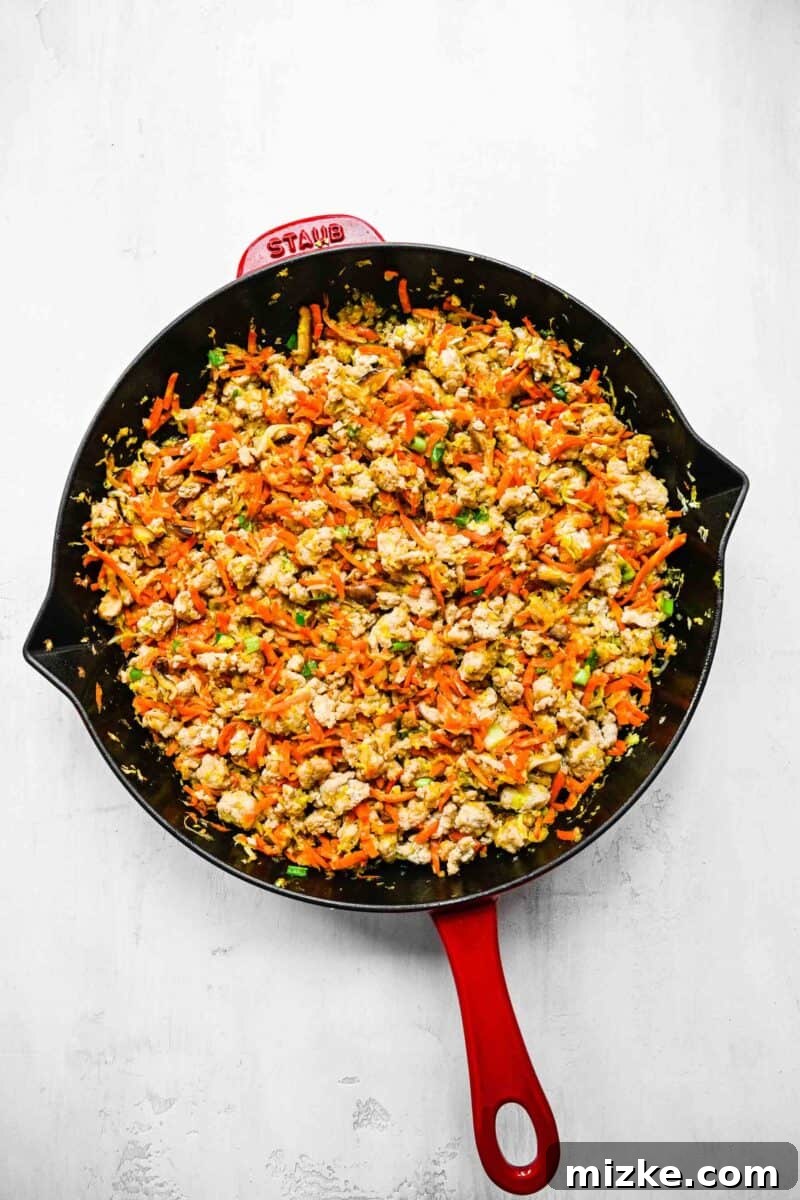 Filling for crispy golden spring rolls; browned ground chicken in a pan with veggies.