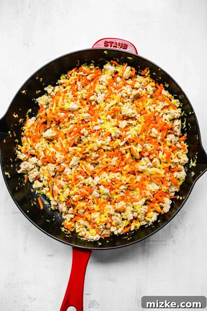 Filling for crispy golden spring rolls; browned ground chicken in a pan with veggies.