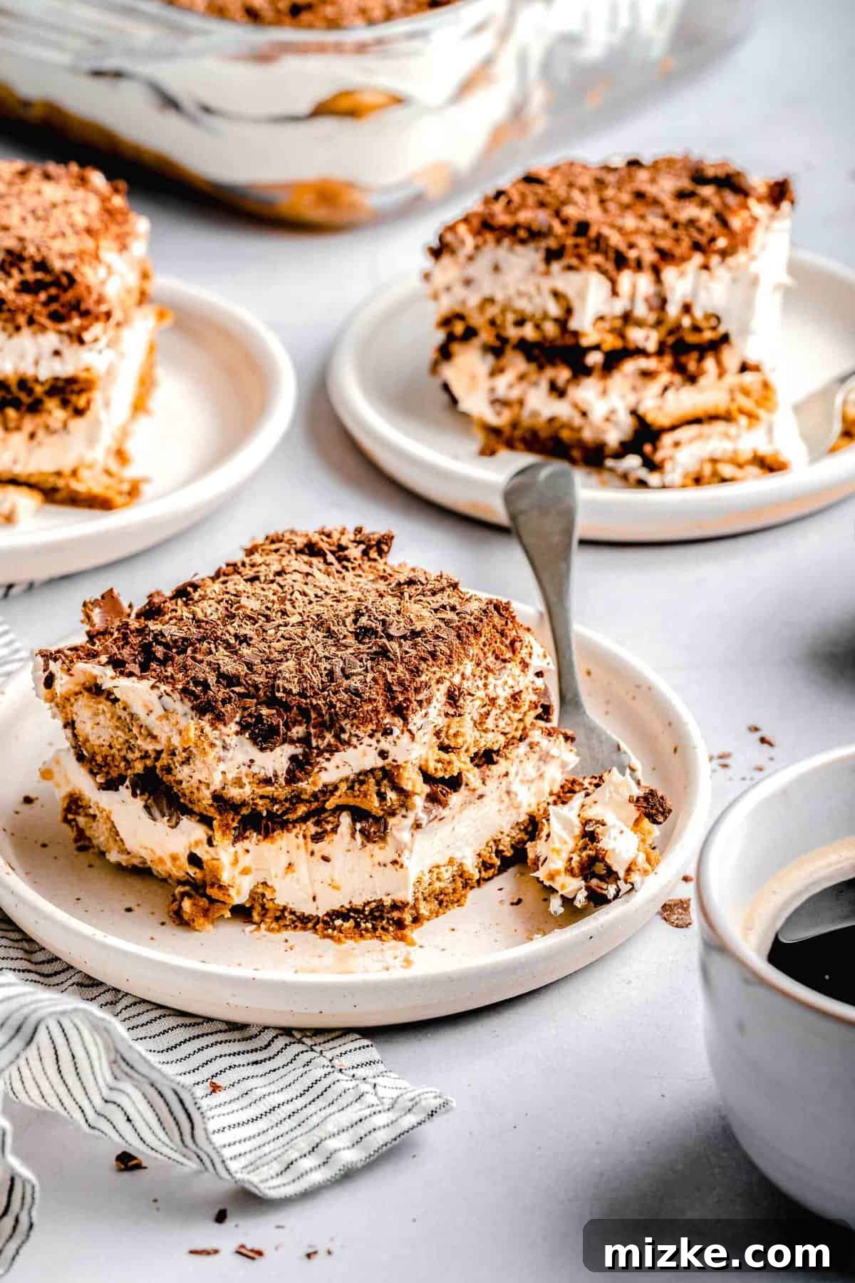 This simple tiramisu is made up of spongy, espresso-soaked ladyfingers layered with a cloudy, creamy mascarpone filling. Slices of tiramisu on plates with forks near a cup of espresso.