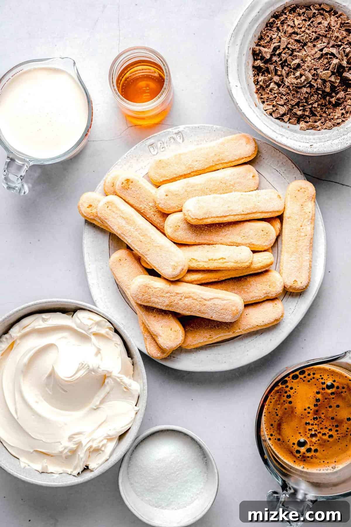 This simple tiramisu is made up of spongy, espresso-soaked ladyfingers layered with a cloudy, creamy mascarpone filling. Ingredients for tiramisu separated into plates, bowls, and measuring cups.