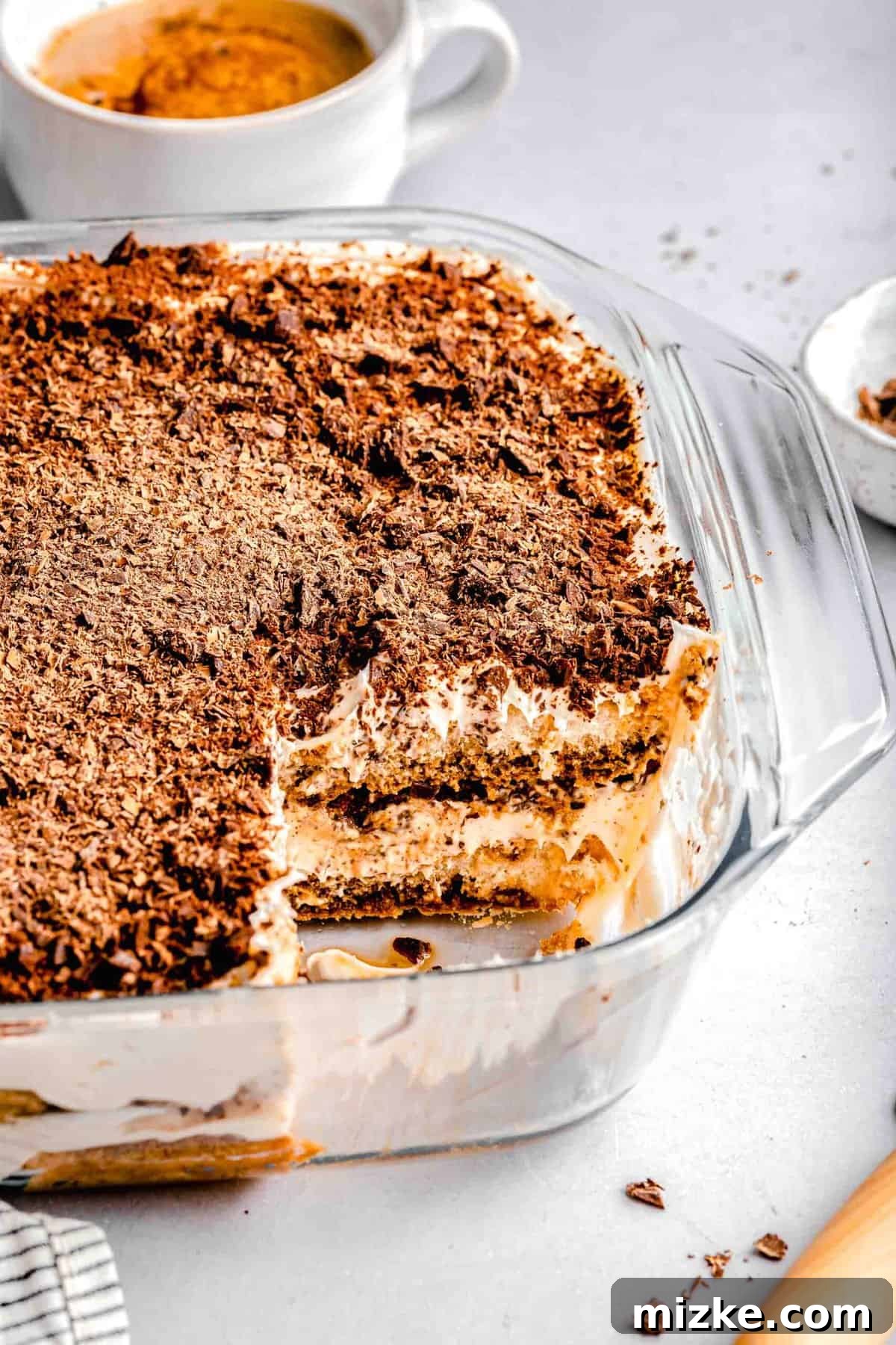 This simple tiramisu is made up of spongy, espresso-soaked ladyfingers layered with a cloudy, creamy mascarpone filling. A baking pan of tiramisu with a slice taken out of it near a cup of espresso.