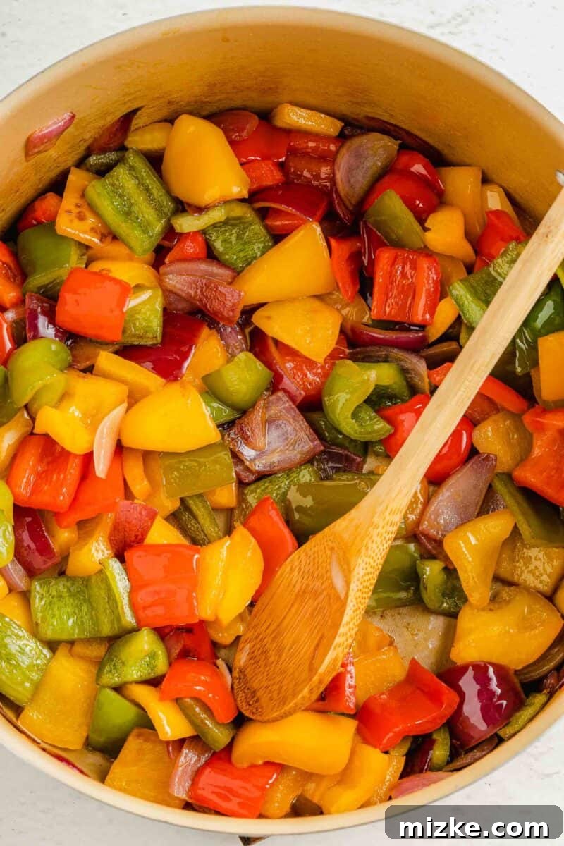 Watch as the medley of colorful vegetables and pineapple softens and caramelizes, building the foundational flavors for your sweet and sour tofu. Vibrant bell peppers, onions, and pineapple chunks gently sautéing in a hot pan, releasing their aromatic flavors and softening to tender-crisp perfection.