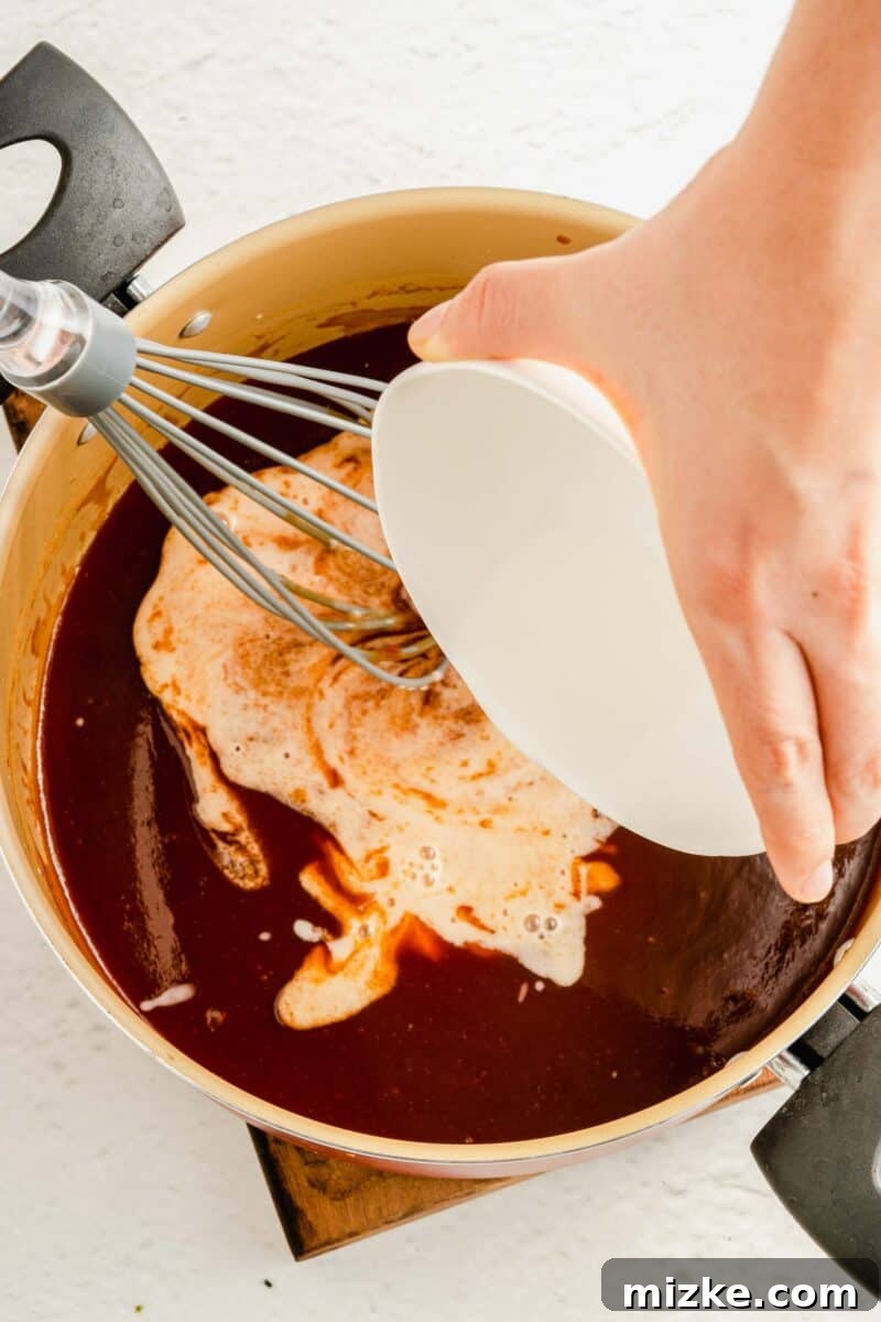 Achieve the perfect sauce consistency by incorporating a cornstarch slurry, ensuring a smooth and glossy finish for your sweet and sour creation. A cornstarch and water slurry being smoothly poured into the rich, vibrant sweet and sour sauce ingredients in a bowl, ensuring a perfectly thickened sauce.