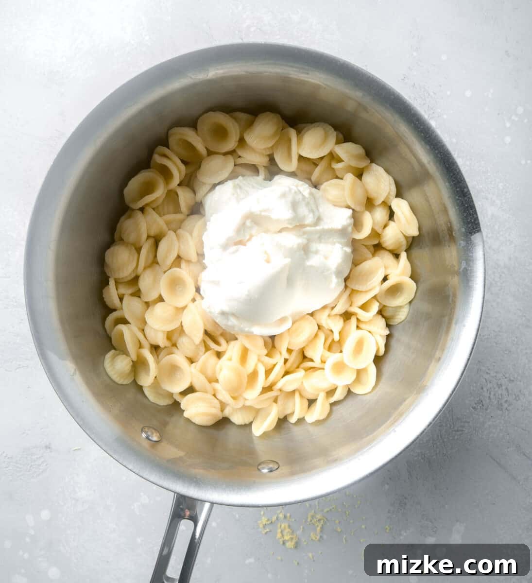 Creamy Lemon Ricotta One-Pot Pasta 4 Ricotta cheese being folded into a stainless steel pot filled with hot, cooked pasta.