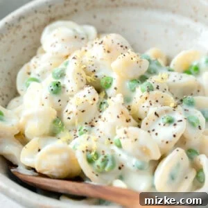 Ricotta and lemon pasta in a bowl with lemon zest and cracked black pepper on top