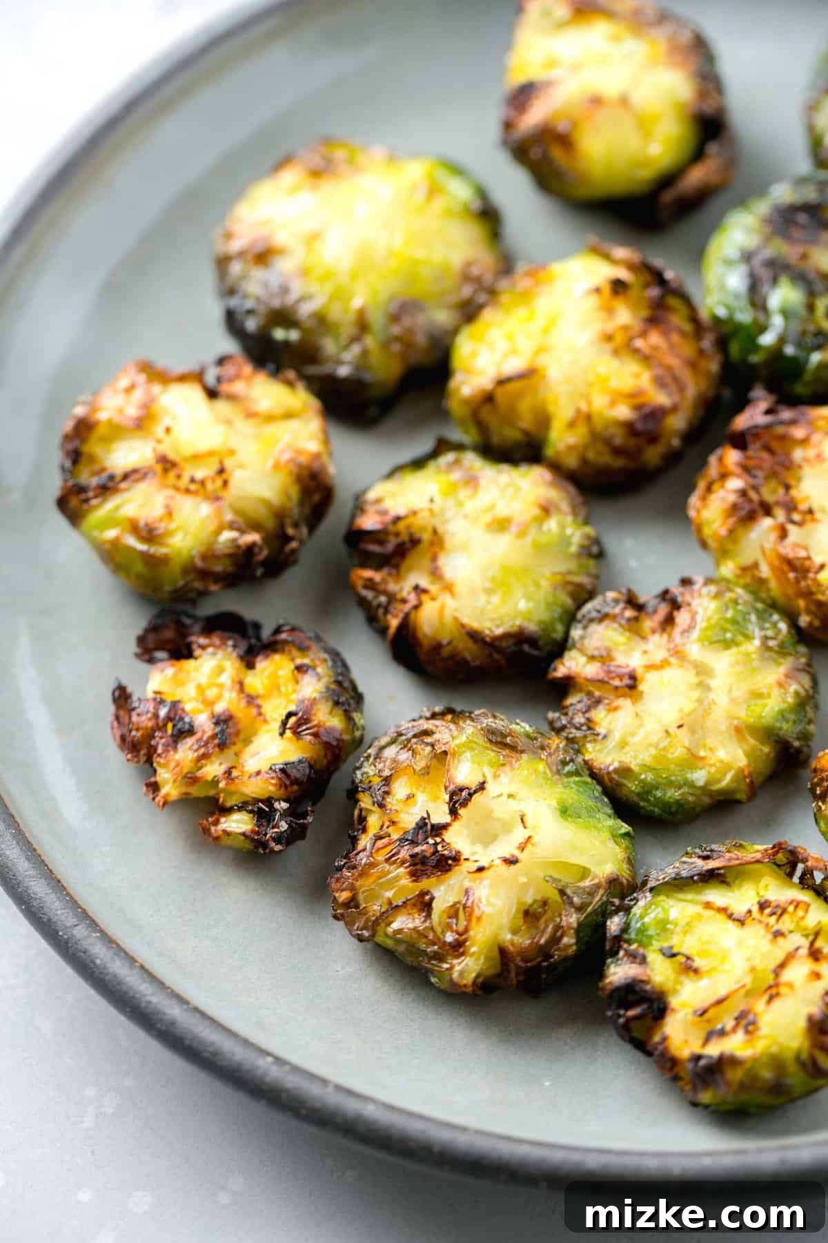 Perfectly Crisped Air Fryer Smashed Brussels Sprouts 2 Crispy and browned-edged smashed Brussels sprouts on a grey ceramic plate, ready to be enjoyed
