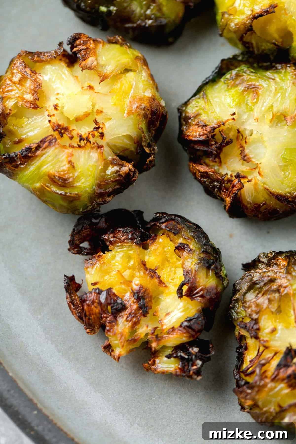 Perfectly Crisped Air Fryer Smashed Brussels Sprouts 3 Close-up of perfectly smashed Brussels sprouts with crispy browned edges on a grey ceramic plate