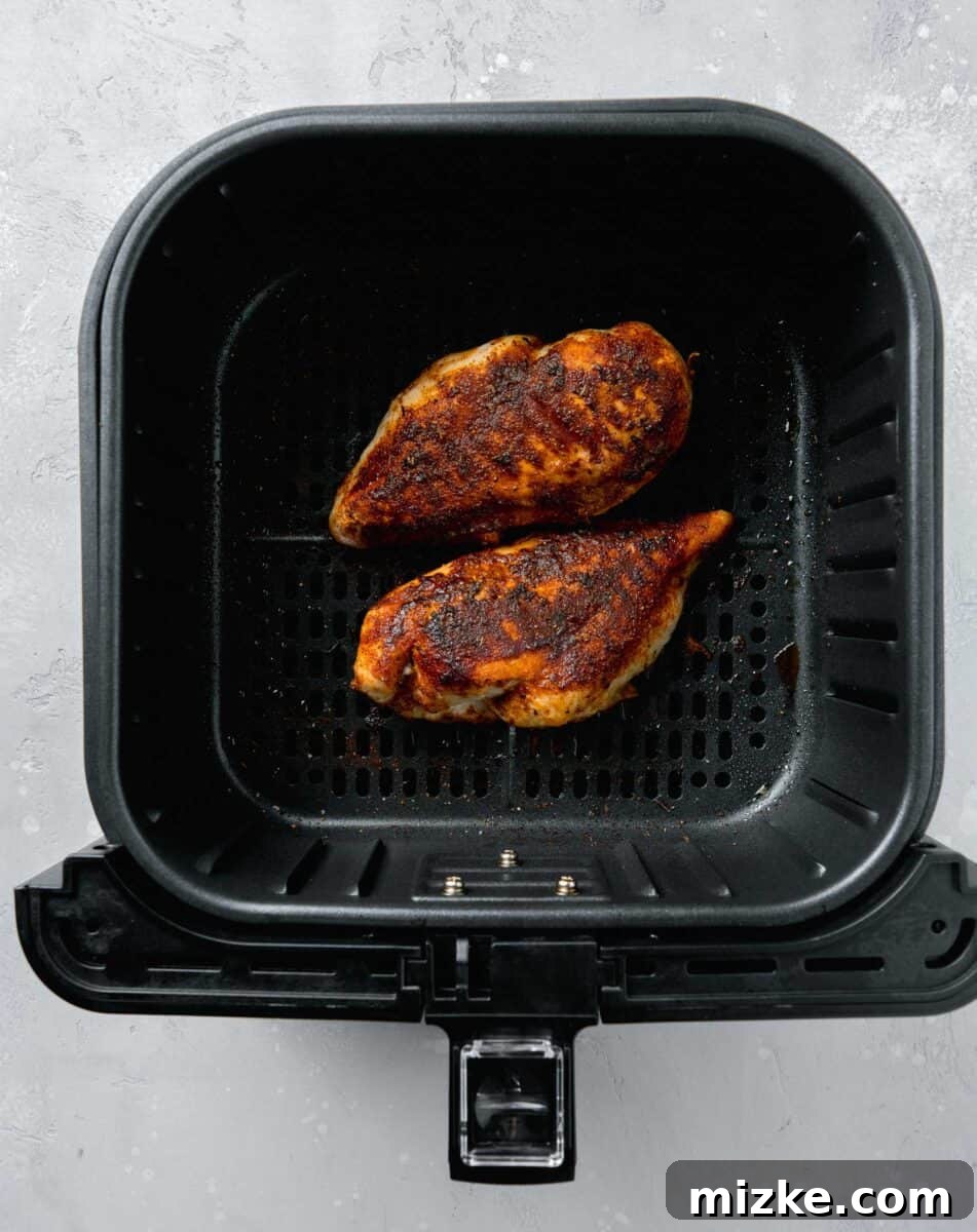 Ultimate Air Fryer Blackened Chicken 5 Perfectly cooked, succulent blackened chicken breasts resting in the air fryer basket after achieving a beautiful, dark crust.