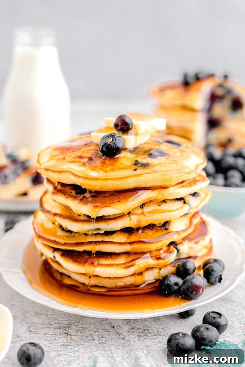 Sweet Blueberry Stacks 10 A decadent stack of golden-brown blueberry pancakes, garnished with a generous pat of melting butter, fresh blueberries, and a cascading pour of maple syrup.