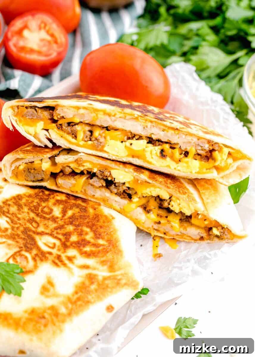 Sunrise Crunch Fold 2 Several golden-brown breakfast crunchwraps, perfectly sealed and ready to eat, are artfully arranged next to fresh, vibrant tomatoes.